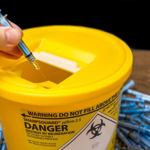 Finger Placing a Needle in a Sharps Pickup Container at a Daytona Beach Pharmacy